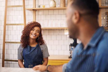 Life begins after coffee. an attractive young businesswoman standing and assisting a customer in her cafe.の写真素材