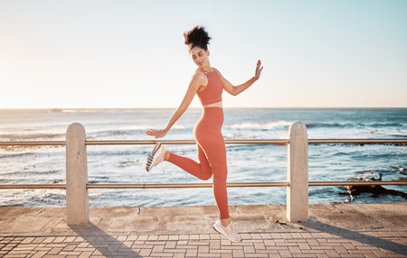 Fitness, happy running and woman jumping on beach path on fun morning exercise with freedom and...