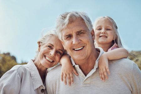 Grandparents, grandchild and portrait in a park for family, love and bonding in nature on blue sky...