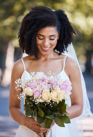 Happy, wedding and smile with black woman and flowers for beauty, celebration and spring event. Smile, makeup and fashion with bride and rose bouquet for marriage, party and outdoor ceremonyの写真素材
