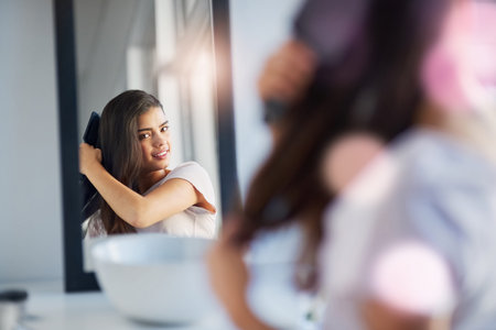 My hair has never looked and felt healthier. a beautiful young woman brushing her hair in the...
