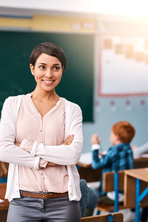 The life of a teacher. a cheerful young female teacher giving class to her students inside a school during the day.の写真素材