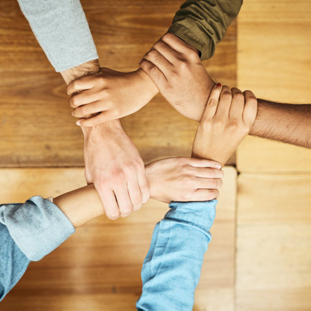 Solidarity. High angle shot of a group of unrecognizable university students holding one anothers...