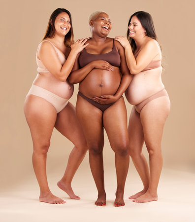 Pregnant body, laughing and women diversity on studio background in empowerment, baby support and community. Smile, happy and pregnancy friends in underwear with funny family planning jokeの写真素材
