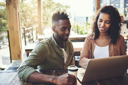 Good company, great connection. a young couple using a laptop together in a coffee shop.の写真素材