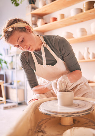 Woman, clay artist and pottery wheel for sculpture design, creative manufacturing and expert focus in studio workshop. Female, mud process and small business designer working with ceramic craftの写真素材