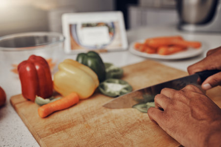 Kitchen, cutting board and vegetables being cut for cooking a healthy, organic and delicious meal. Food, nutrition and chef chop or preparing fresh produce peppers for a diet dinner, lunch or supper.の写真素材