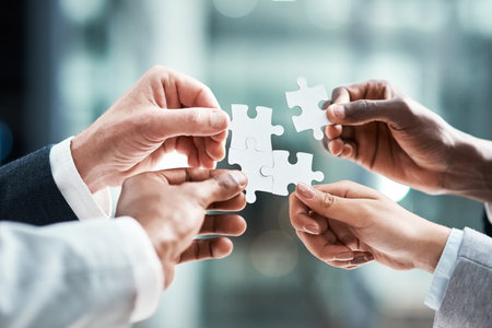 Our team makes for the perfect fit. Closeup shot of a group of unrecognizable businesspeople holding puzzle pieces together.の写真素材