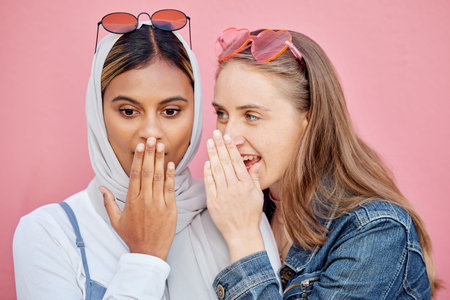 Woman, friends and gossip in shock for secret whisper in ears against pink studio background. Women...