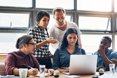 Reviewing their latest designs. a group of businesspeople working together on a laptop in an office.