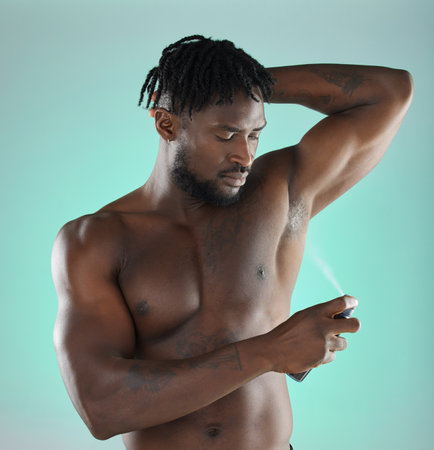 Body hygiene and black man with deodorant spray product for self care routine of people in studio. Health, wellness and cosmetic grooming of person with skincare at isolated green background.の写真素材