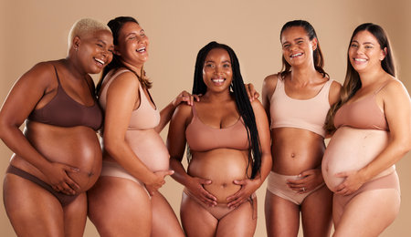 Pregnancy body, portrait or laughing women on studio background in diversity empowerment, baby support or community. Smile, happy or pregnant friends in underwear with stomach in funny jokeの写真素材
