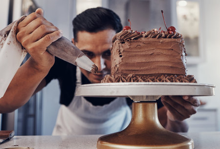 Piping, chef and man baker baking a cake with chocolate in a kitchen or pastry cook preparing a...