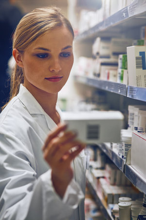 She has the knowledge and personality of a good pharmacist. an attractive young woman working in a pharmacy.の写真素材