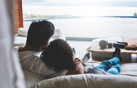 Home is where you put your feet up. Rearview shot of a relaxed couple enjoying the day at home together.の写真素材