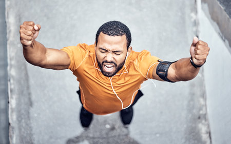 Top view, black man and achievement for exercise, outdoor and celebration for target, happiness and fitness. African American male, runner or athlete with motivation, workout or training goal in cityの写真素材