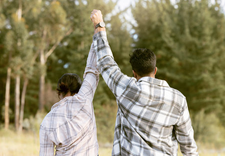 Success, hiking and back of couple holding hands in forest for achievement, victory or fitness goals. Travel, freedom and man with woman celebrating milestone, journey and adventure goal in natureの写真素材