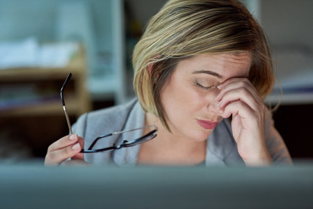 Shes been looking at that screen for far too long. a businesswoman looking stressed while working late in the office.の写真素材