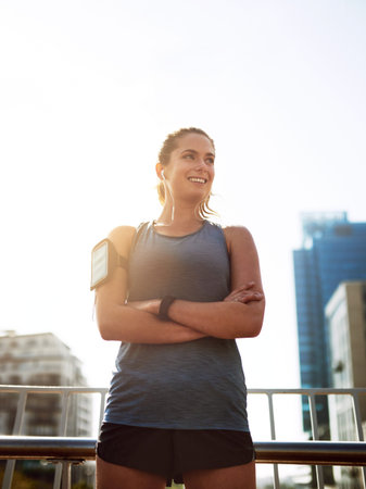 Shes in training. a sporty young woman standing with her arms folded outdoors.