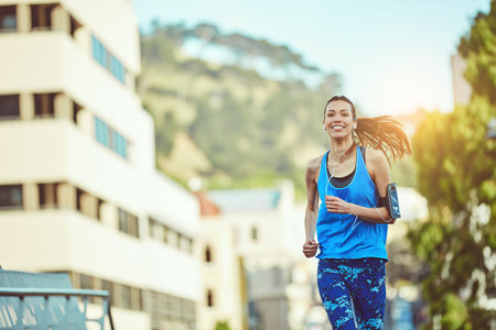 Run and be happy. a young woman out in the city for her morning run.