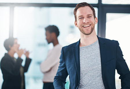 I motivate my team with a positive attitude. Portrait of a businessman in an office with his colleagues in the background.の写真素材