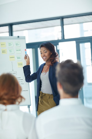 Working through ways to maximise their business growth. a young businesswoman giving a presentation to her colleagues in an office.の写真素材