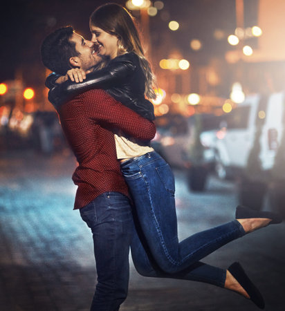 Most love stories start in the city. a happy young couple standing together outside at night.