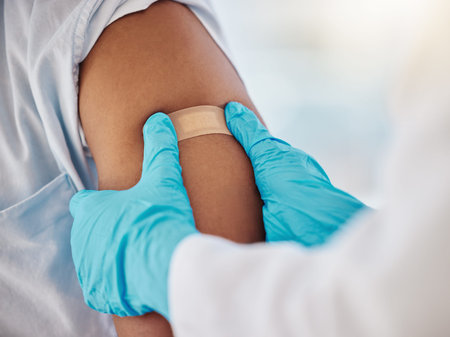 Covid, vaccine and plaster on the arm of a black man patient in a hospital for an injection or...