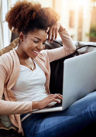 Comfy, connected and contented. a relaxed young woman using a laptop on the sofa at home.の写真素材