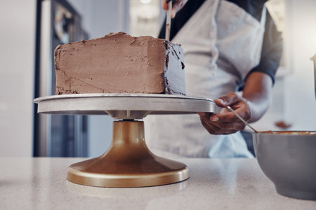 Hand, cake and cooking with a man chef working in a kitchen while preparing dessert for a party...