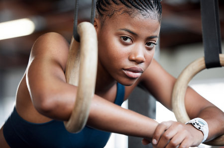 Fitness, gymnastics and portrait of black woman with rings for training, exercise and workout at gym. Wellness, motivation and face of girl athlete with focus for competition, performance and sportsの写真素材