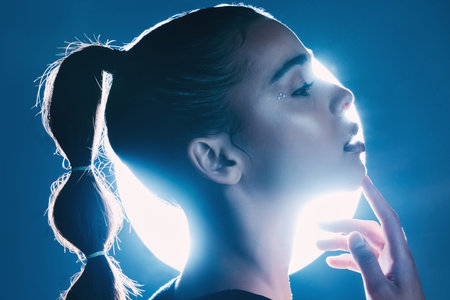 Makeup, cyberpunk and face of a girl with lighting isolated on a dark background in a studio. Idea,...
