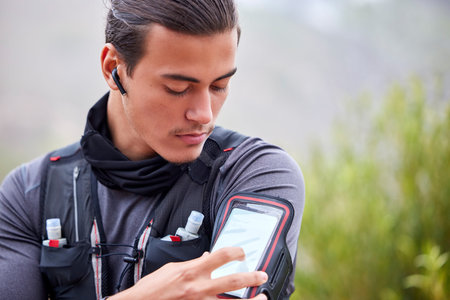 Fitness, phone and man hiking outdoor, trekking in nature with earpods, music and workout with...