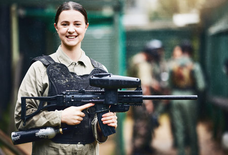Paintball, happy and portrait of woman with gun in safety uniform for outdoor shooting game with...