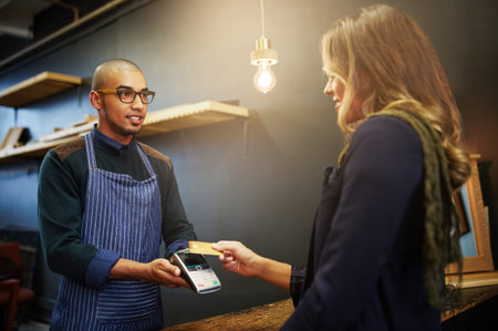 The easiest way to pay. a customer paying using NFC technology in a shop.