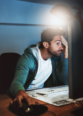 What went wrong now. a young designer looking stressed out while working late in the office.