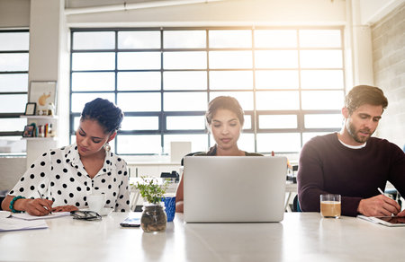 100 committed to their work assignments. a team of colleagues working at a desk in a modern office.