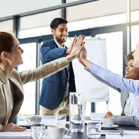 Together we achieve so much more. a group of businesspeople high-fiving in the boardroom.