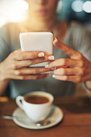 Shell be good to go after a cup of joe. a young woman sending an sms while working late in her office.の写真素材