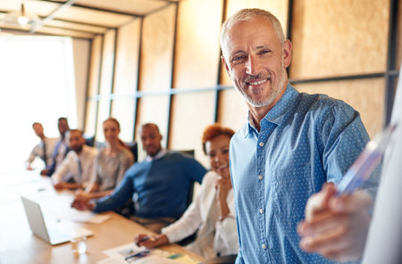 Meeting their targets through great strategizing. a mature businessman delivering a presentation during a boardroom meeting.の写真素材