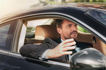Can you go. a handsome businessman looking annoyed while driving into work.
