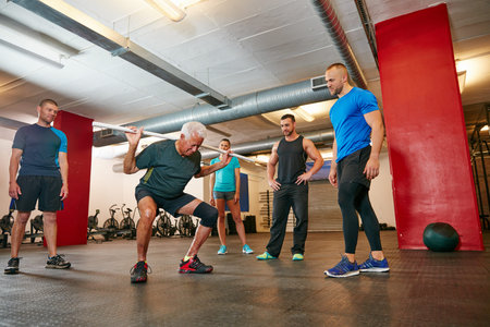 The struggle is worth the benefits. a senior man doing pvc exercises while a group of people watch...