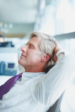 Business man relaxing after work. Side view of mature business man resting at work.の写真素材