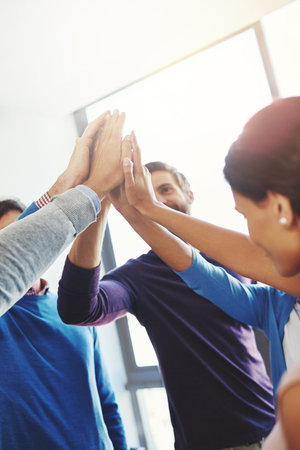 They make a great team. a group of businesspeople giving each other a high five.