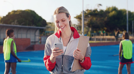 Hockey, coach and woman with phone at group training at a stadium for fitness, match and game. Sports, trainer and female laughing at meme, text or online message during morning cardio with playersの写真素材