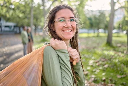 Plastic bag, park and happy woman for eco friendly cleaning on earth day, community service or...