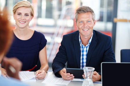Leading his team with expertise. A mature male manager sitting in a meeting with his team.の写真素材