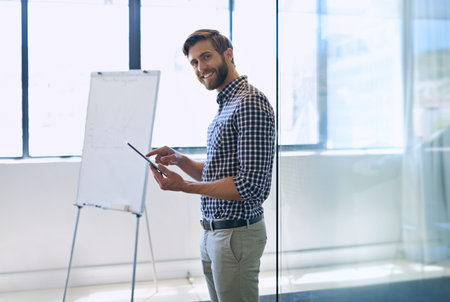 Marketing solutions in the digital age. a handsome businessman standing with a tablet in his office.