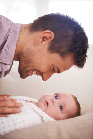 Could you be any cuter. Side view of a young father holding and looking at his adorable baby girl.