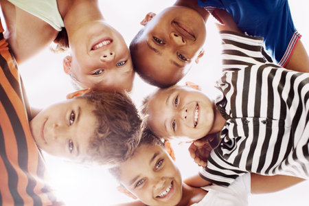 Friends together at recess. Low view of a group of schoolchildren looking down at you and huddling together.の写真素材